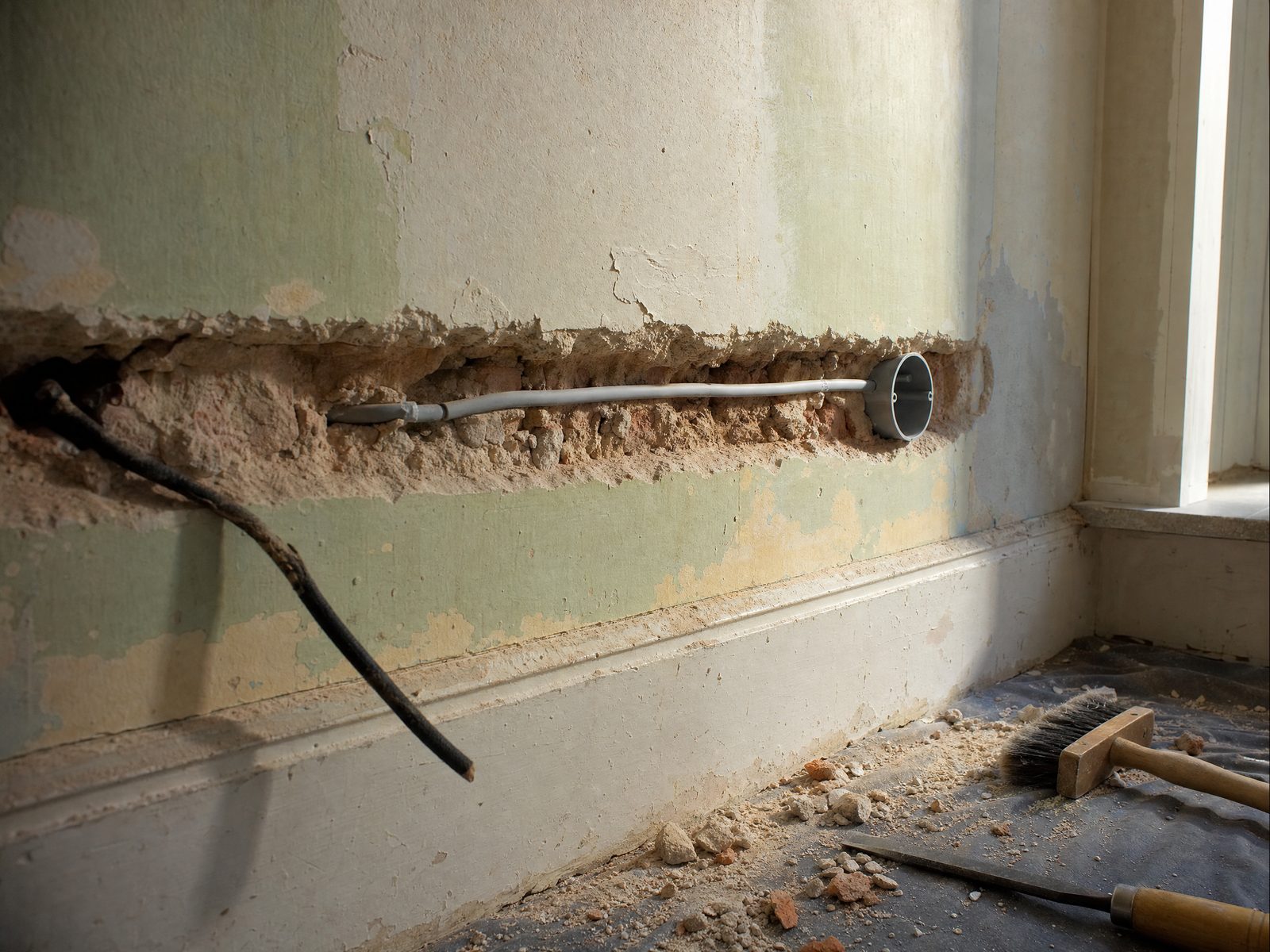 Altbauzimmer während der Elektrosanierung: neue Leitung an der alten Kalkputzwand, Aufputzdosen gesetzt, Boden abgedeckt