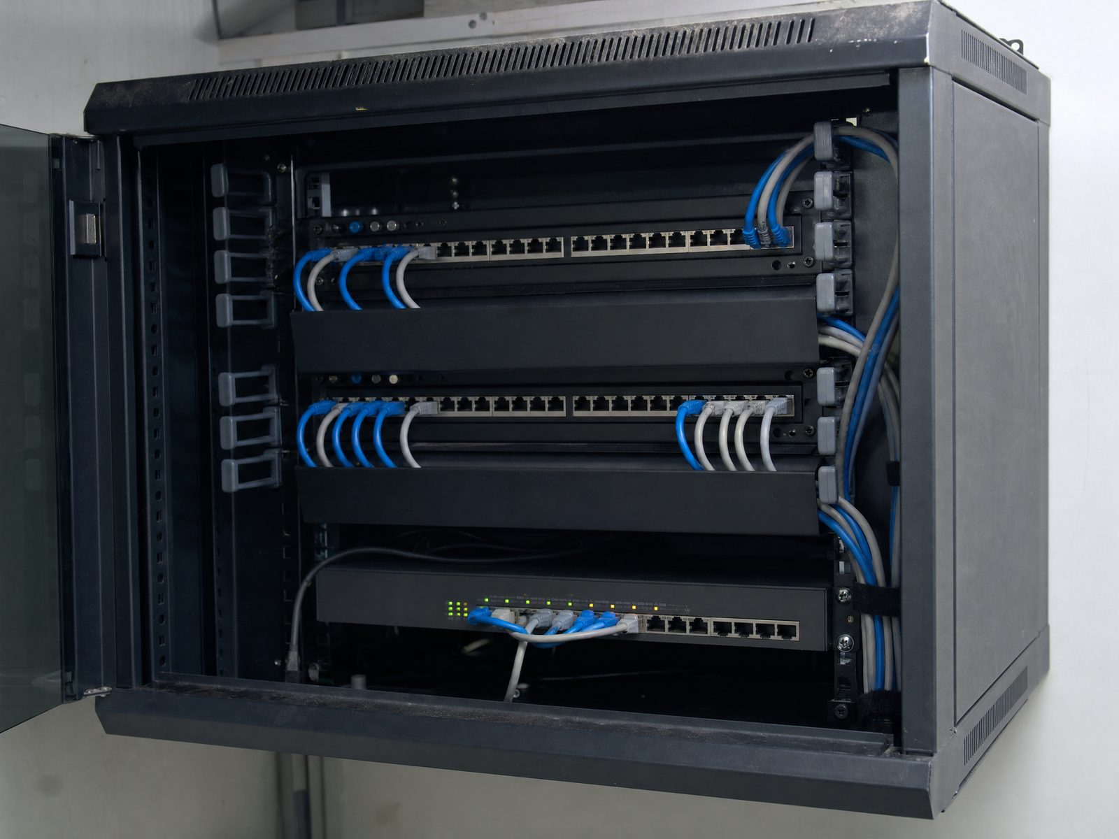 Patchfeld aus der Nähe: blaue Netzwerkkabel stecken in einer Reihe und sind zu einem parallelen Bündel zusammengefasst